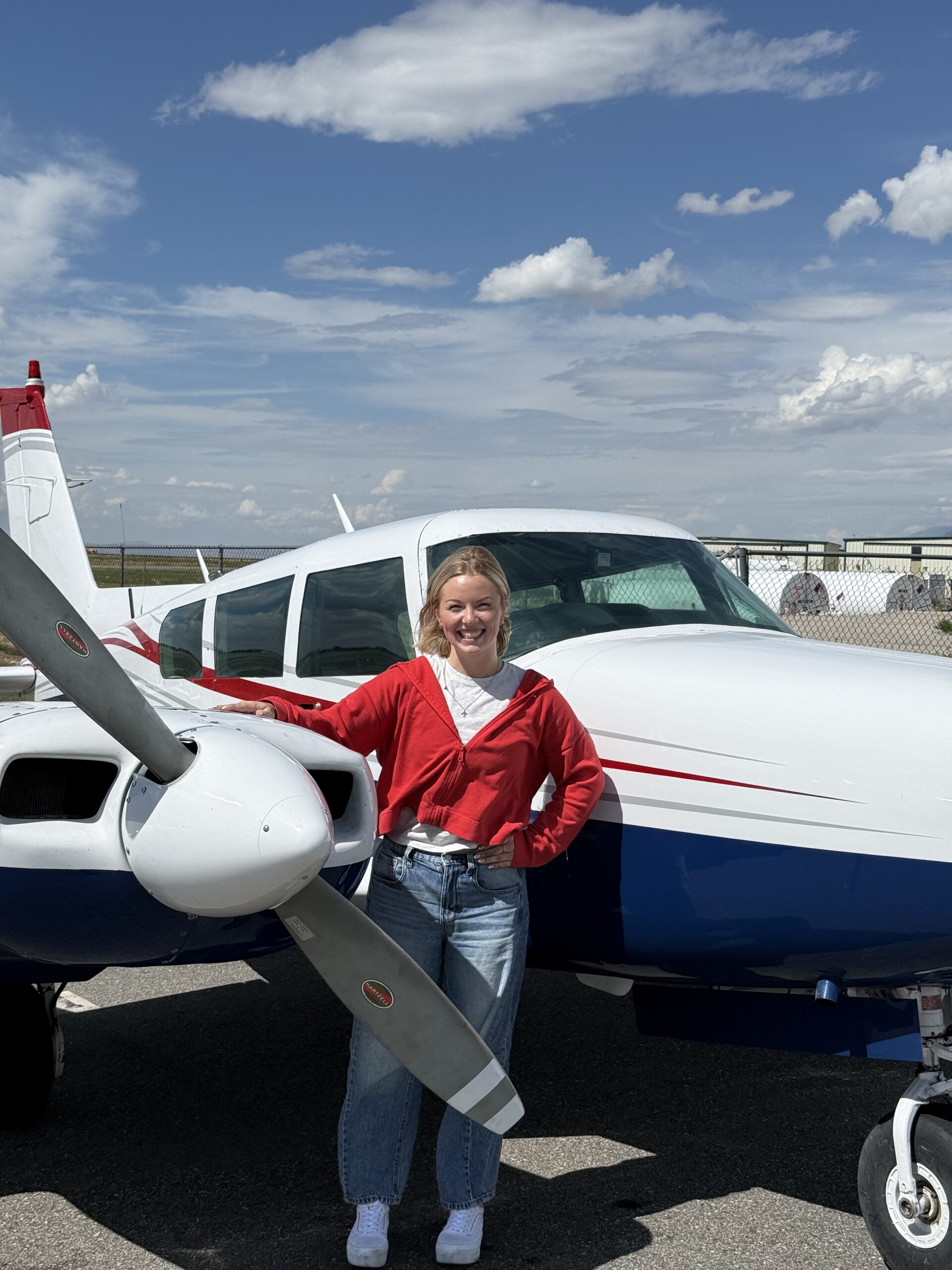 Smiling Axiom Aviation student next to a twin-engine airplane on the ramp